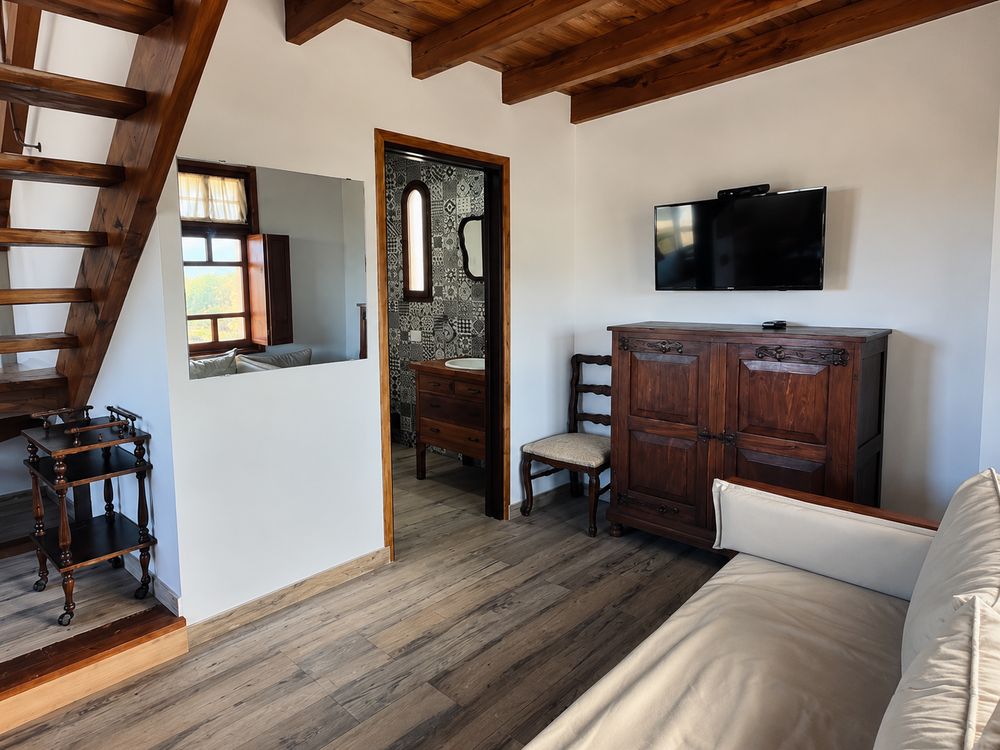 Living con sillón, tele y escalera de madera